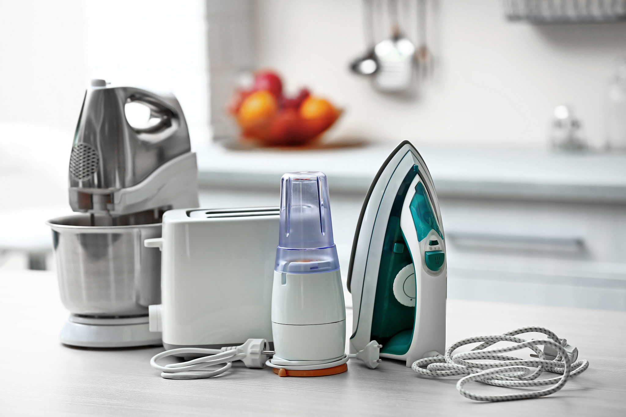 A kitchen counter with an Iron, Toaster, Mixer, and a onion slicer.
