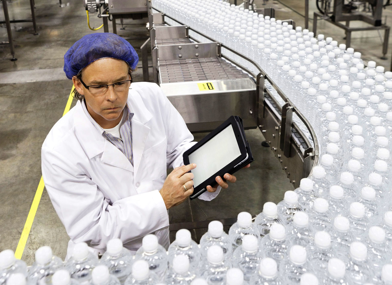 man observing a water bottle production line.
