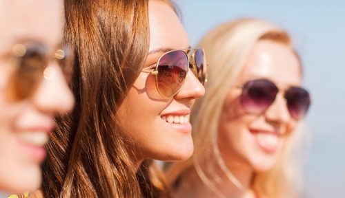 Drei Frauen, die lächeln und eine Sonnenbrille tragen