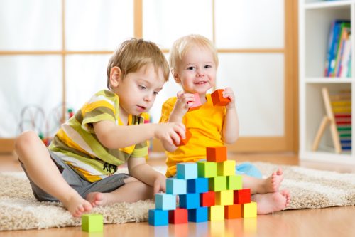 Preschooler children playing with colorful toy blocks.